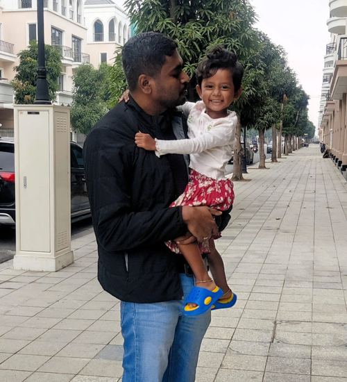 Manjunath holding his daughter on a street abroad